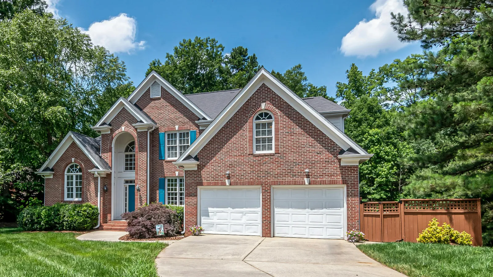 Brick two-story home with gray shingle roof and two garage doors