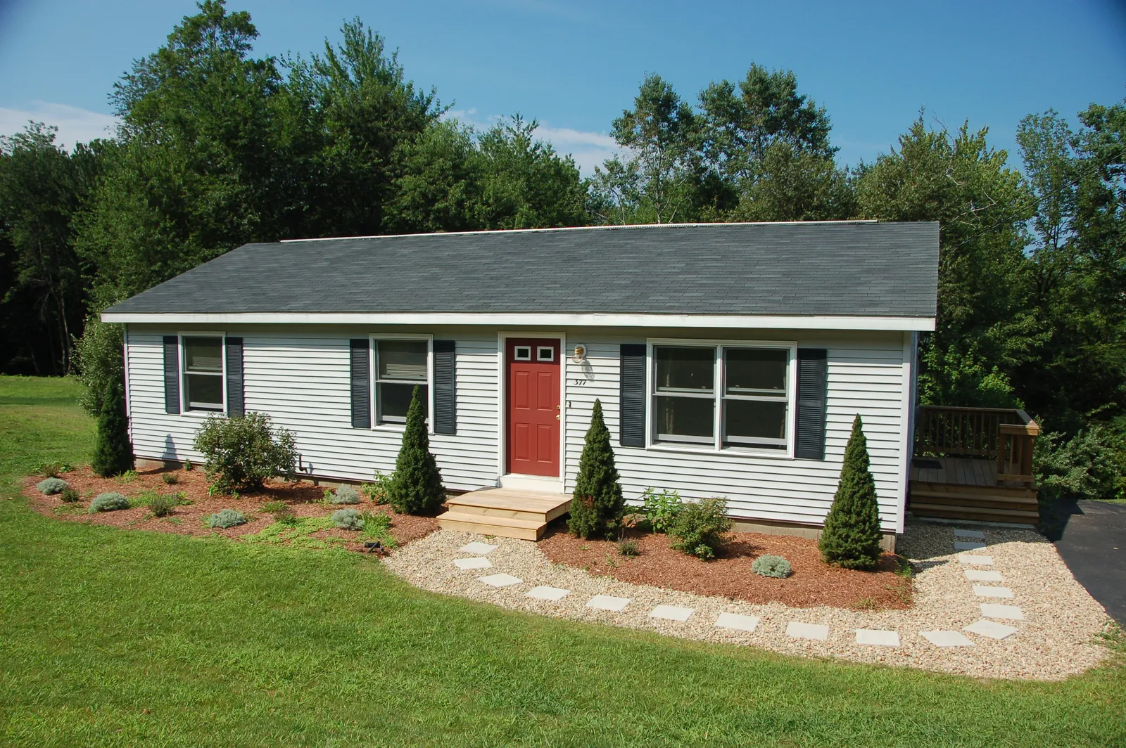 Dark shingle roof and red front door on a small ranch home