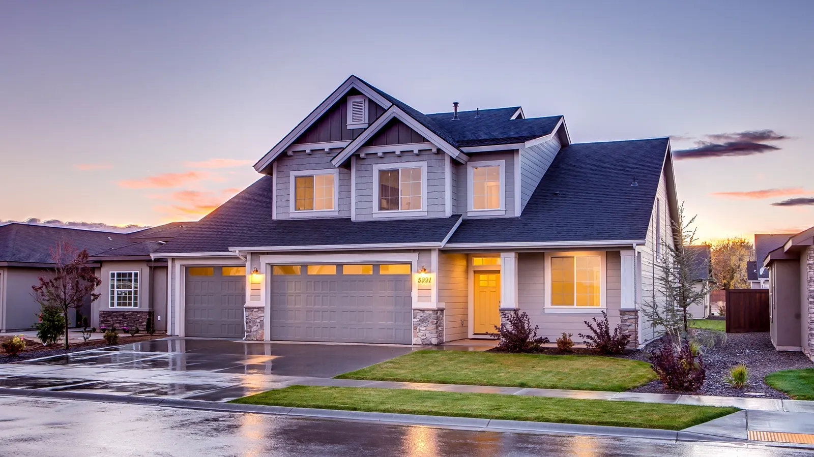 Gray two-story home with dark shingle roof at dusk