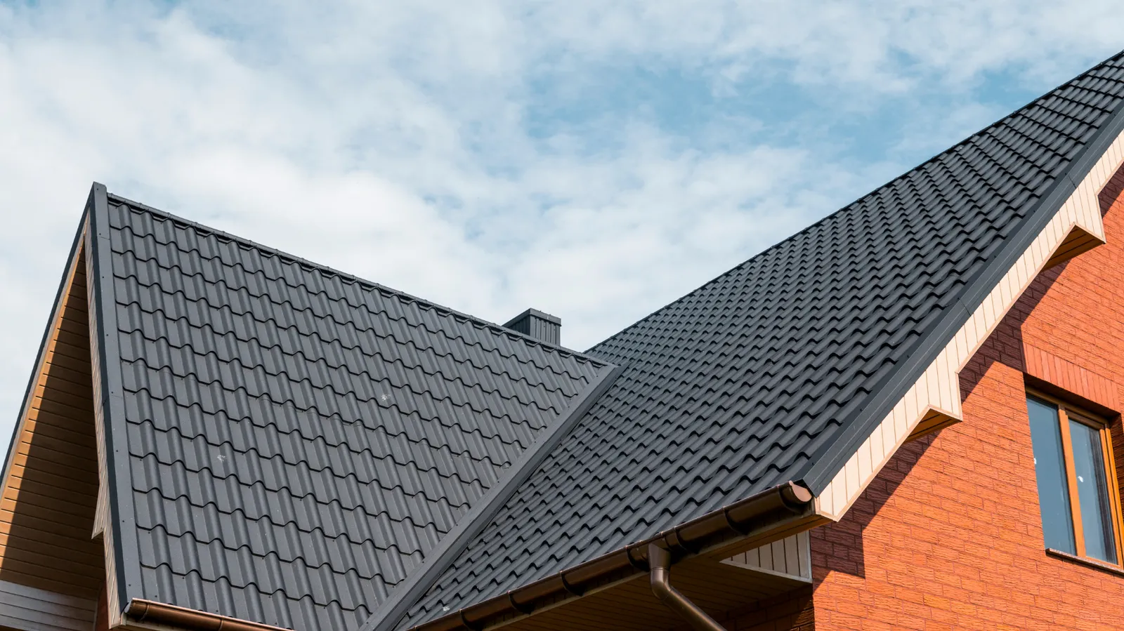 Steep gable peak finished with dark metal tile roofing panels